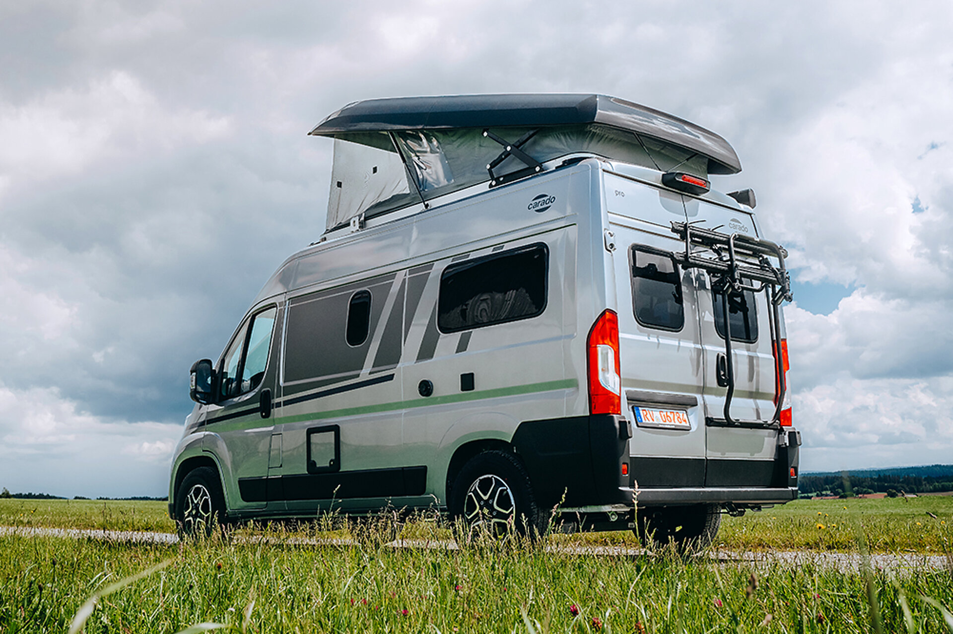 Heckansicht eines Camper Vans mit Aufstelldach in einer Wiese.