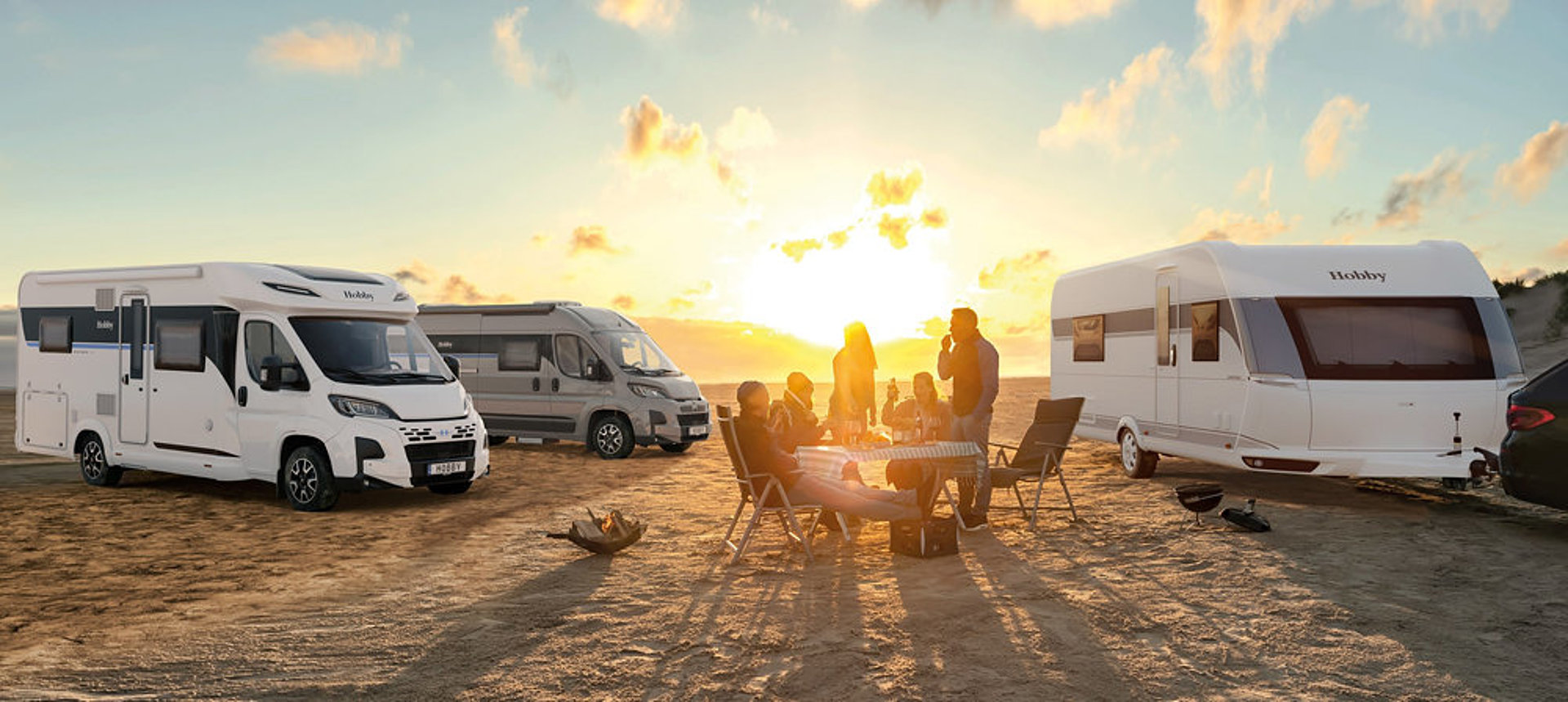 Mehrere Camping-Fans treffen sich mit ihren Mietfahrzeugen am Strand.