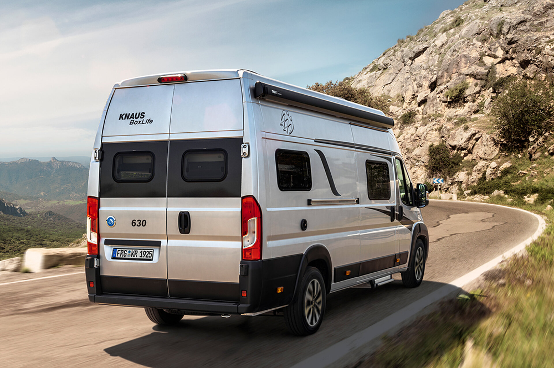 Heckansicht eines KNAUS BOXLIFE, der eine Straße entlang fährt.