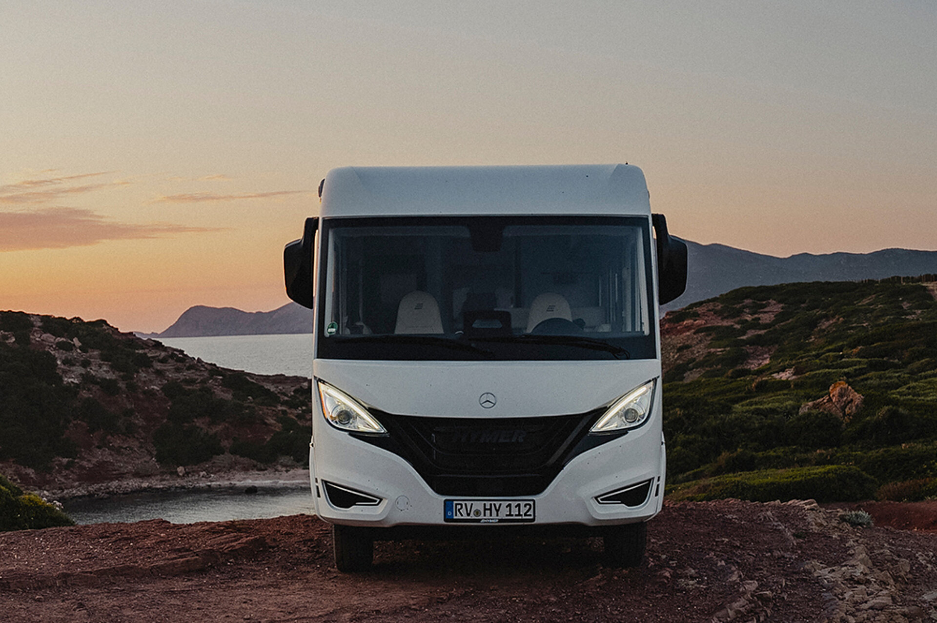 Teilintegriert. Integriert. Vollendet. Ein integrierter HYMER B-Klasse ModernComfort steht vor einer Küste im Sonnenuntergang.