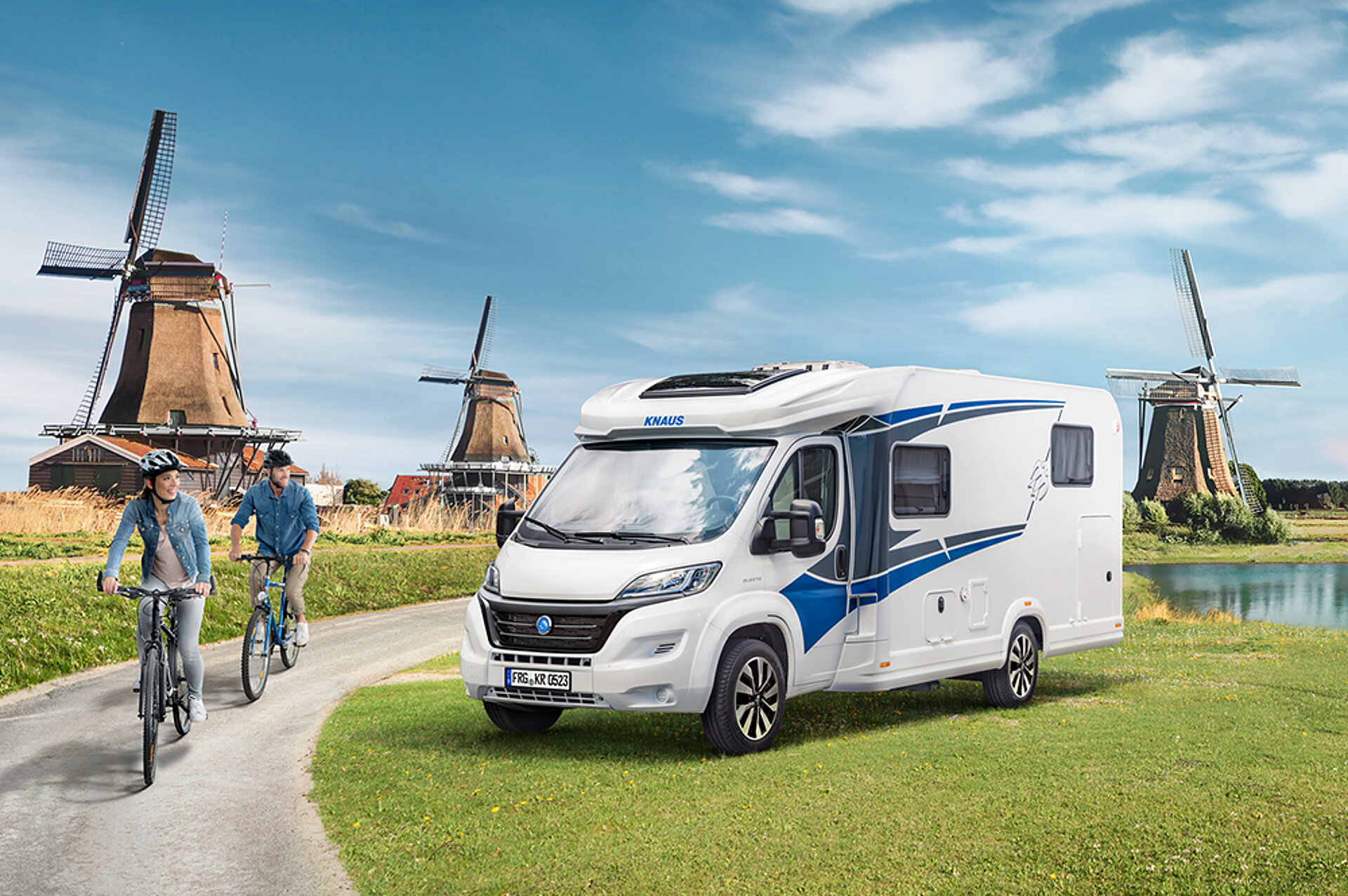 Ein Paar fährt mit dem Fahrrad an einem KNAUS L!VE TI Wohnmobil vorbei.