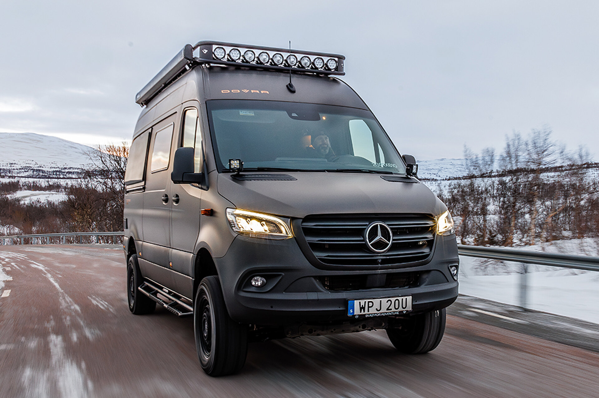 Ein Offroad-Kastenwagen fährt eine winterliche Straße entlang.