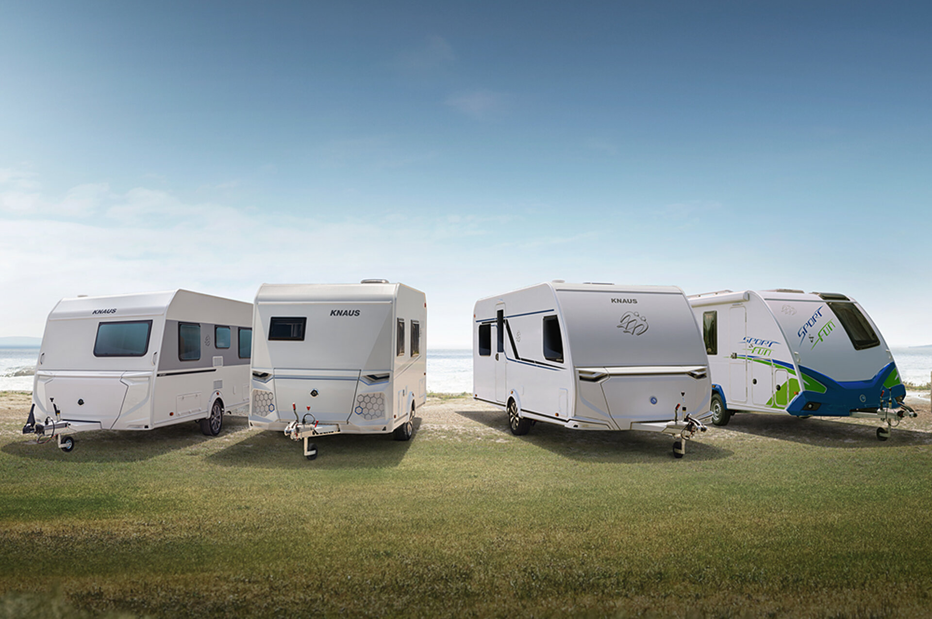 The four caravan series from KNAUS stand side by side in a meadow.