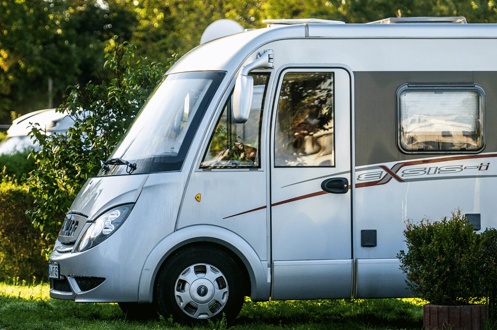 Wohnmobil steht auf einem Hof im Grünen