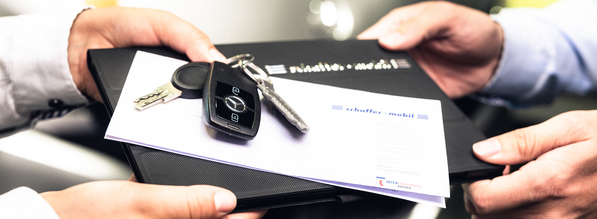 Prodejce společnosti schaffer-mobil předává kupujícímu dokumenty potřebné k registraci obytného vozu.