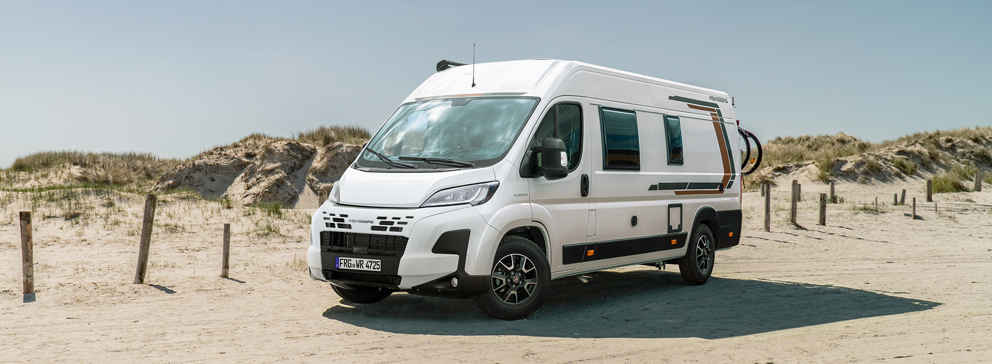 Ein WEINSBERG Kastenwagen parkt am Strand.