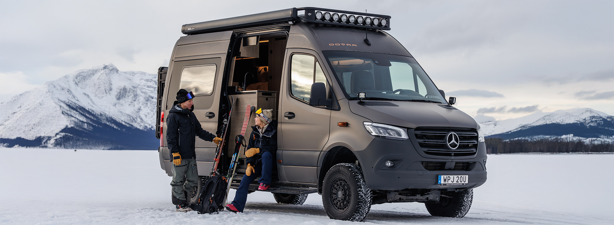 Zwei Menschen sitzen an der Seitentür eines Dovra Offroad-Campers.