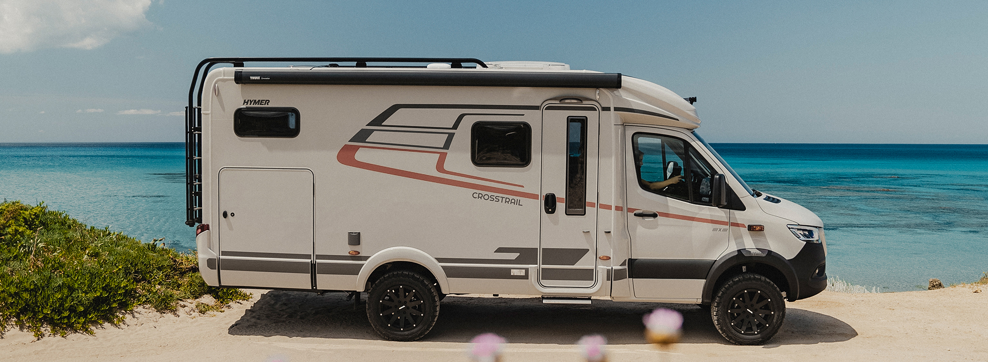 Karavan HYMER ML-T stojí na slunném pláži.