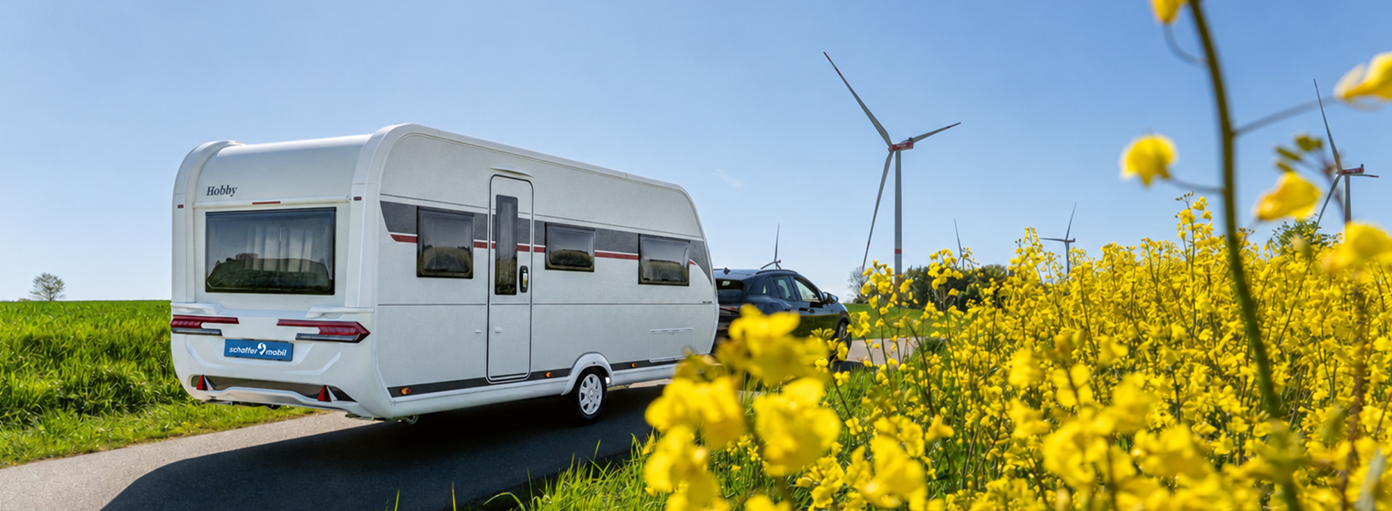 Ein Hobby DE LUXE Wohnwagen wird durch ein Rapsfeld gezogen.