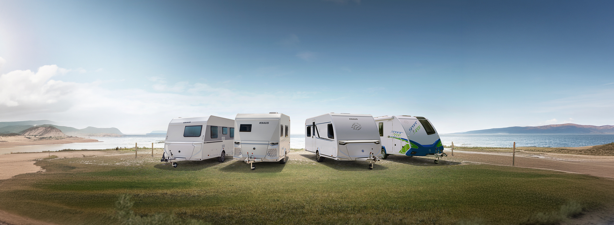 Die vier Wohnwagen-Baureihen von KNAUS stehen nebeneinander auf einer Wiese.