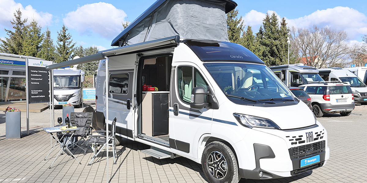 Erleben Sie die Möglichkeiten Ihres Carado Wohnmobils! Ein Carado Camper Van steht samt Markise und Sitzgelegenheit auf dem Gelände von schaffer-mobil.