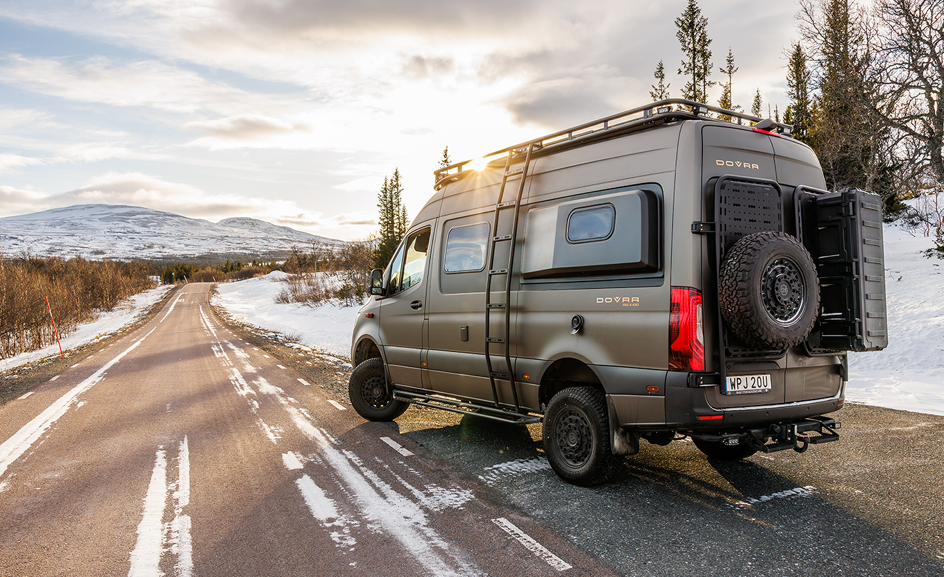 Heckansicht eines Dovra Offroad Kastenwagens, der an einer Straße in einer Winterlandschaft parkt. 