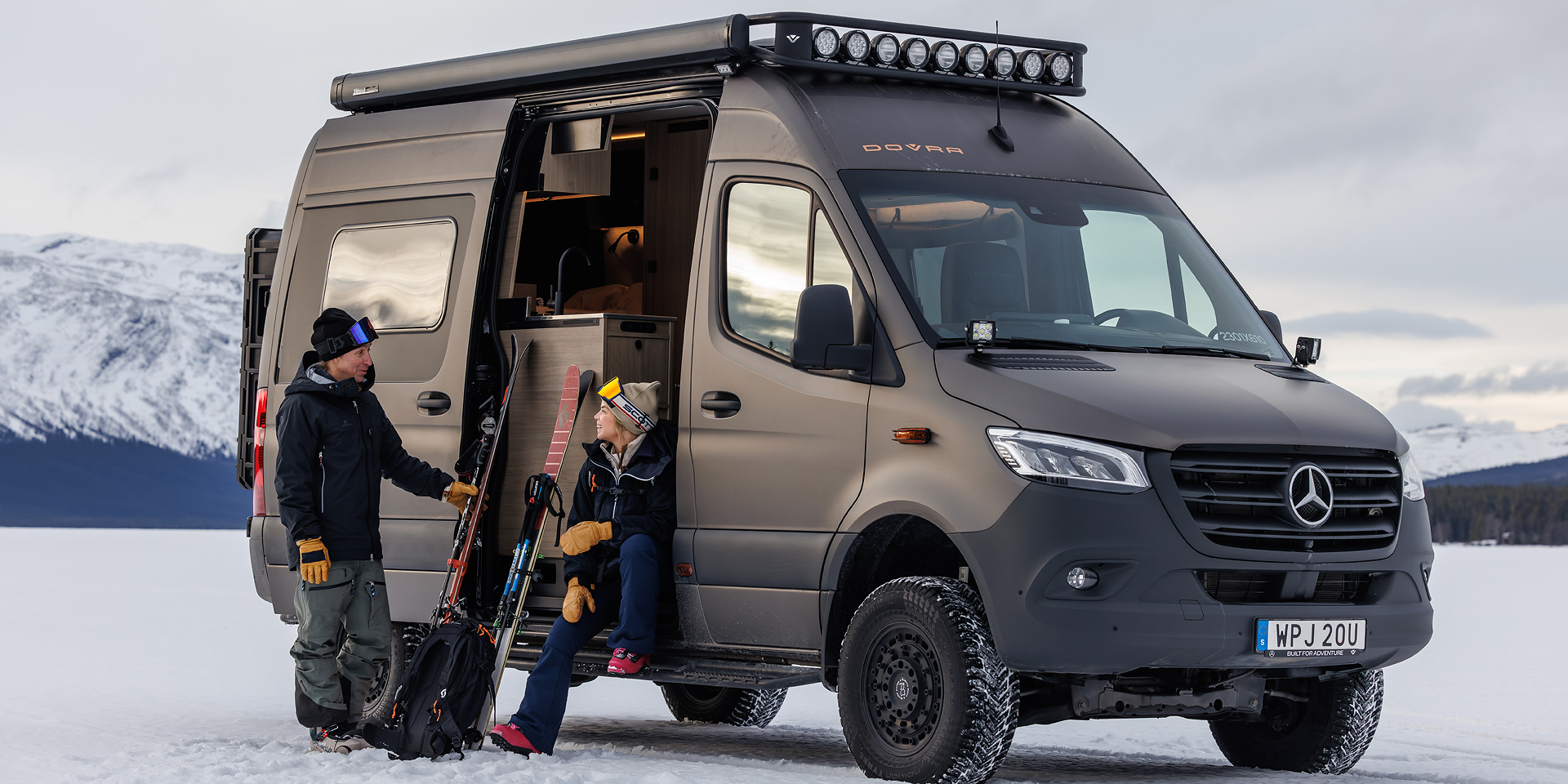 Zwei Menschen sitzen an der Seitentür eines Dovra Offroad-Campers.